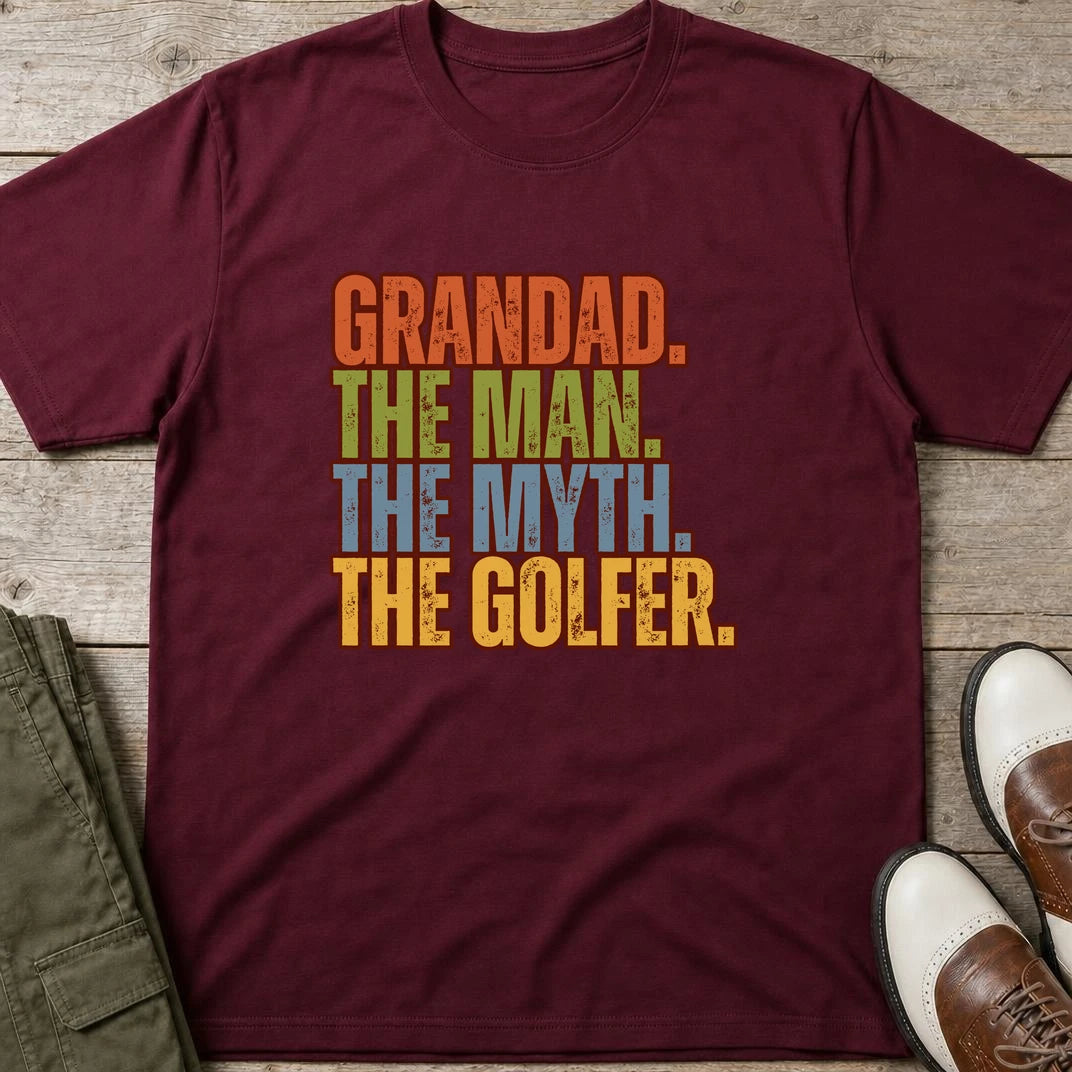 Grandad Golfer T-Shirt in Maroon lying on a plain floor. T-shirt is a unisex cut and 100 per cent cotton.