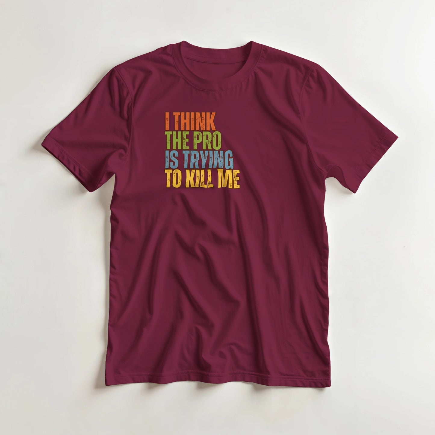 The Pro T-Shirt in Maroon lying on a plain floor. T-shirt is a unisex cut and 100 per cent cotton.