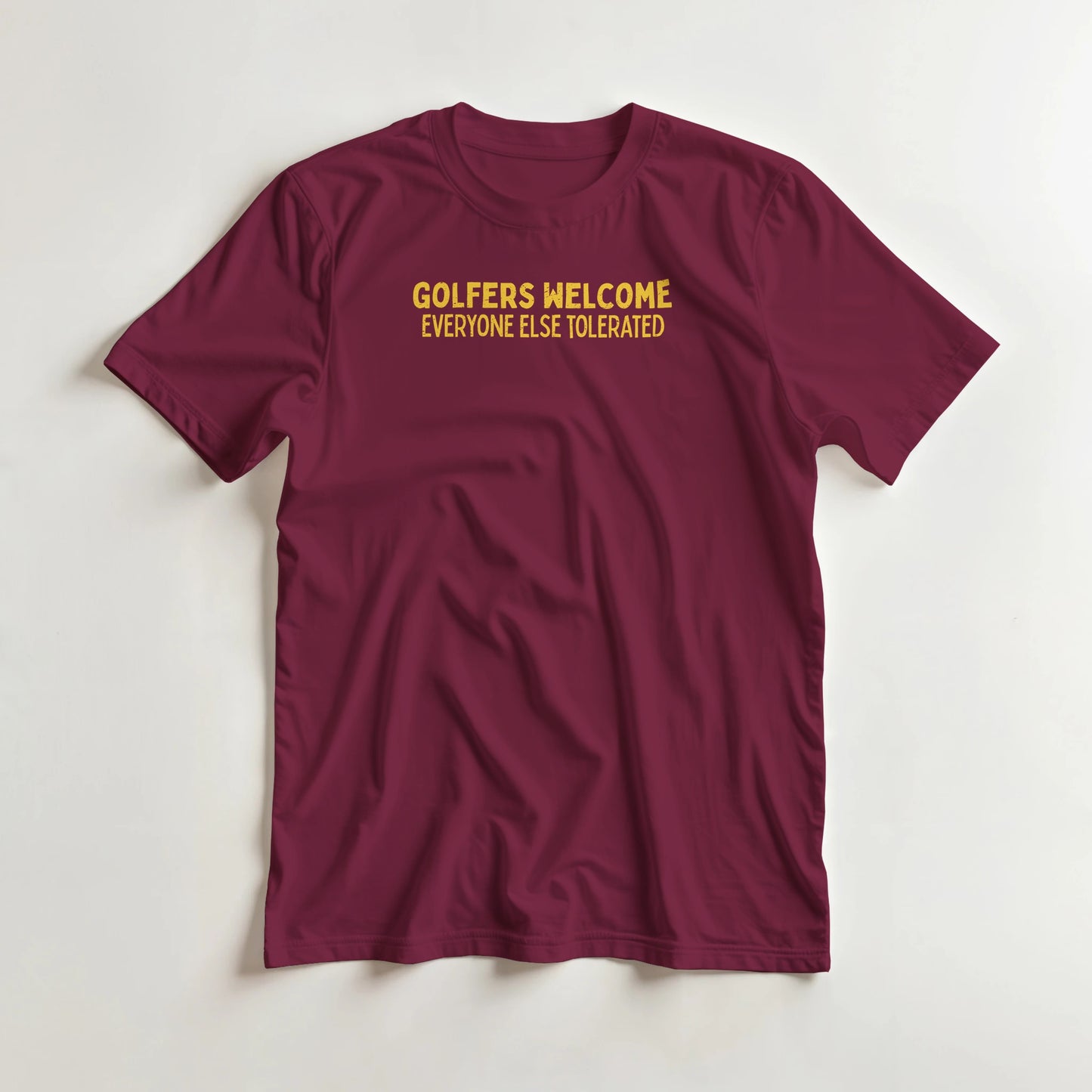 Golfers Welcome T-Shirt in Maroon lying on a plain floor. T-shirt is a unisex cut and 100 per cent cotton.