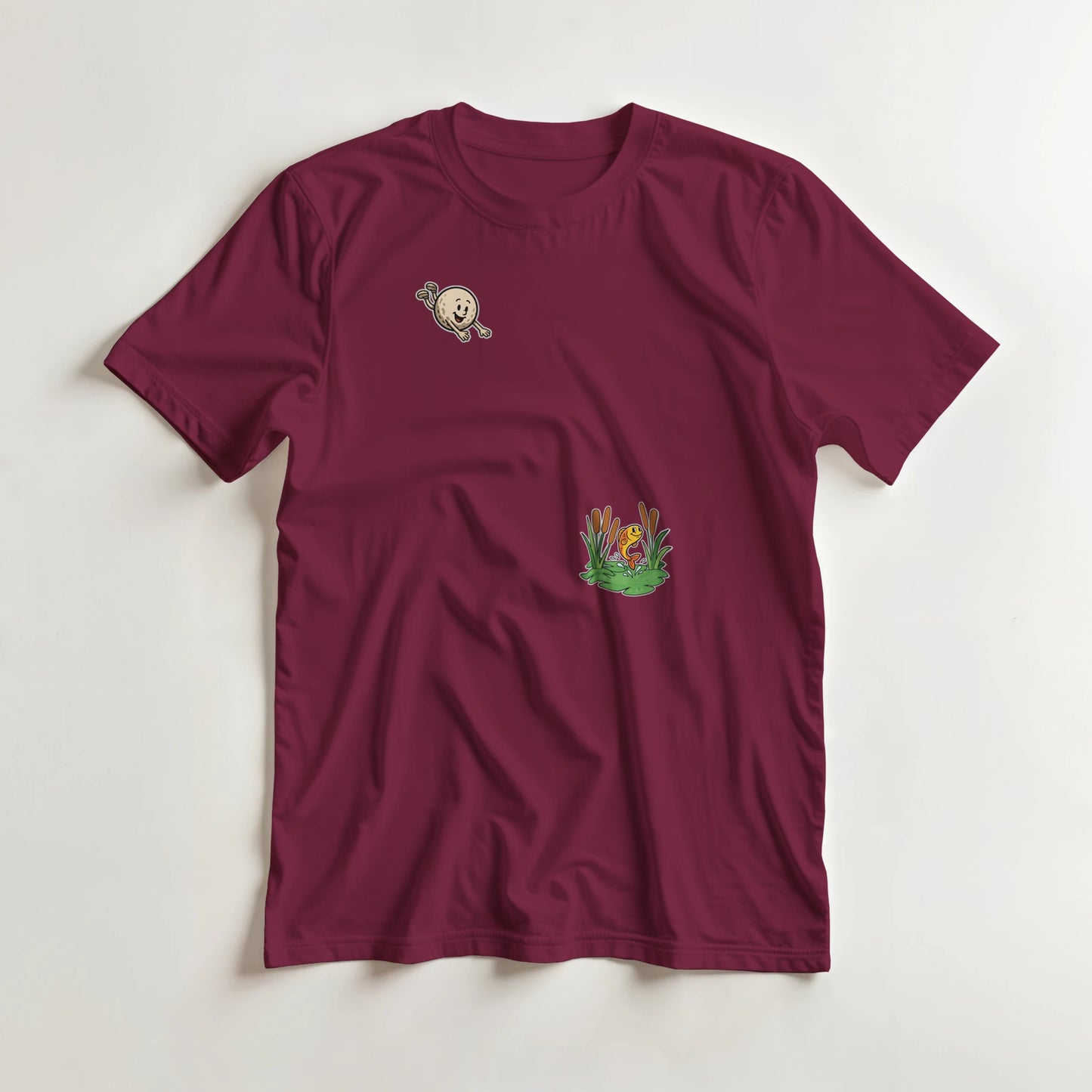 Flying Golf Pond T-Shirt in Maroon lying on a plain floor. T-shirt is a unisex cut and 100 per cent cotton.