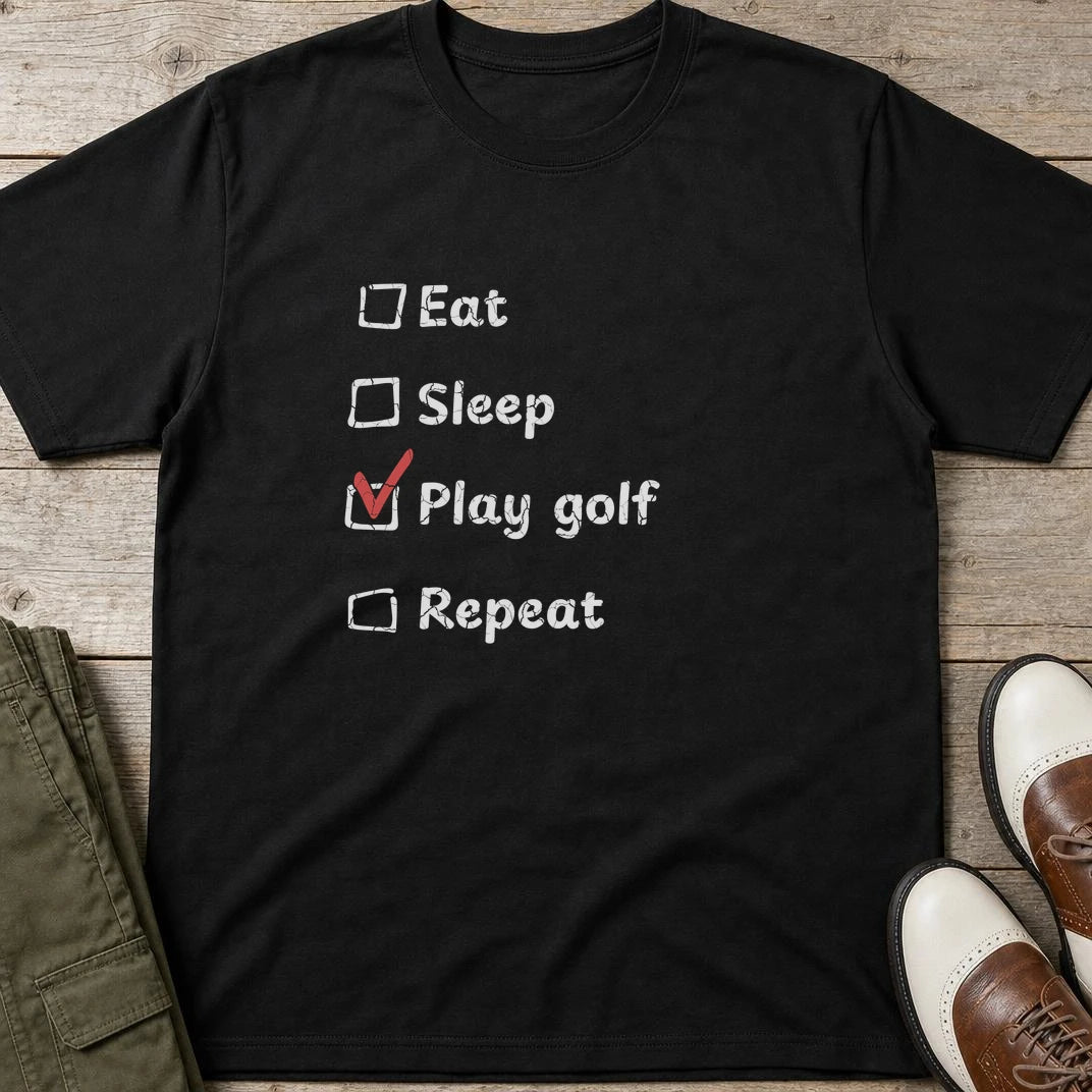 Golf Repeat T-Shirt in Black lying on a plain floor. T-shirt is a unisex cut and 100 per cent cotton.