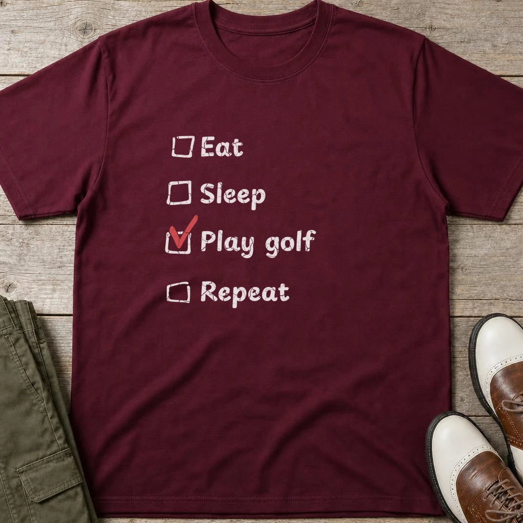 Golf Repeat T-Shirt in Maroon lying on a plain floor. T-shirt is a unisex cut and 100 per cent cotton.