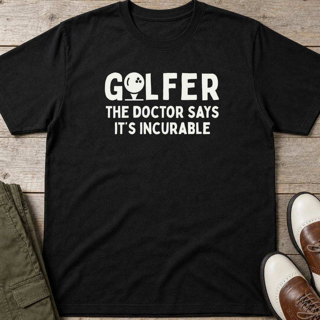 Golfer Incurable T-Shirt in Black lying on a plain floor. T-shirt is a unisex cut and 100 per cent cotton.