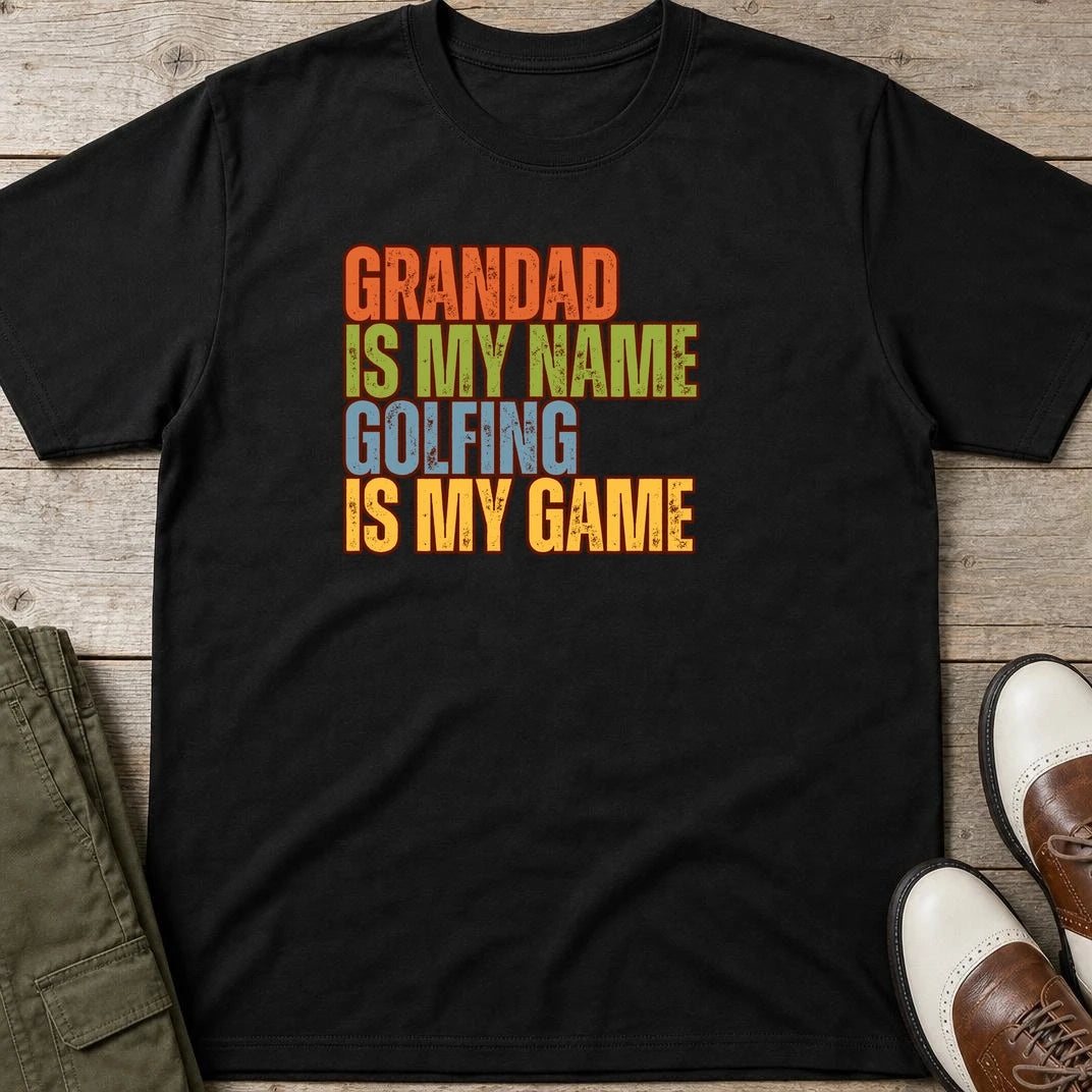 Grandad Golfing T-Shirt in Black lying on a plain floor. T-shirt is a unisex cut and 100 per cent cotton.