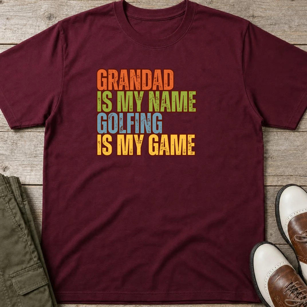 Grandad Golfing T-Shirt in Maroon lying on a plain floor. T-shirt is a unisex cut and 100 per cent cotton.