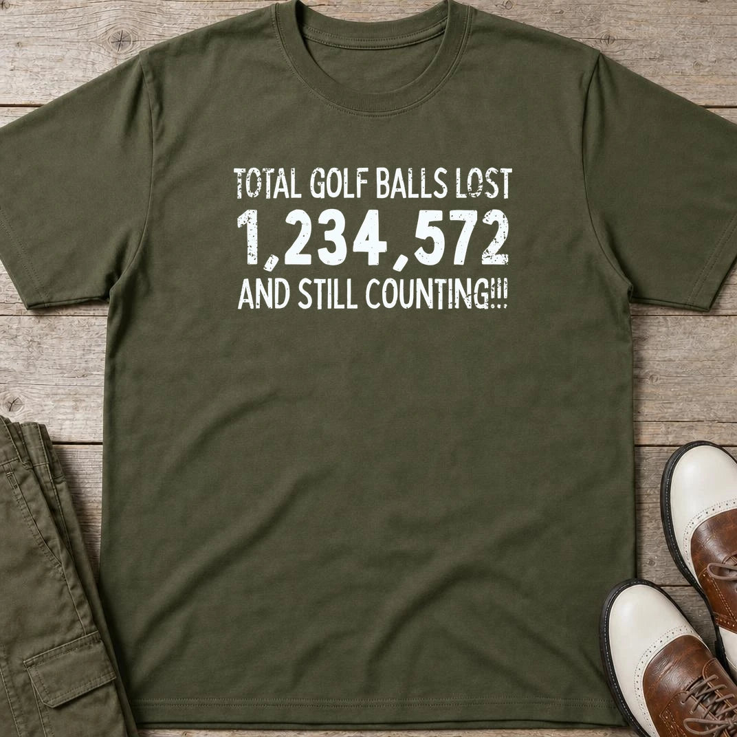 Golf Balls Lost 1,234,572 T-Shirt in Military Green lying on a plain floor. T-shirt is a unisex cut and 100 per cent cotton.