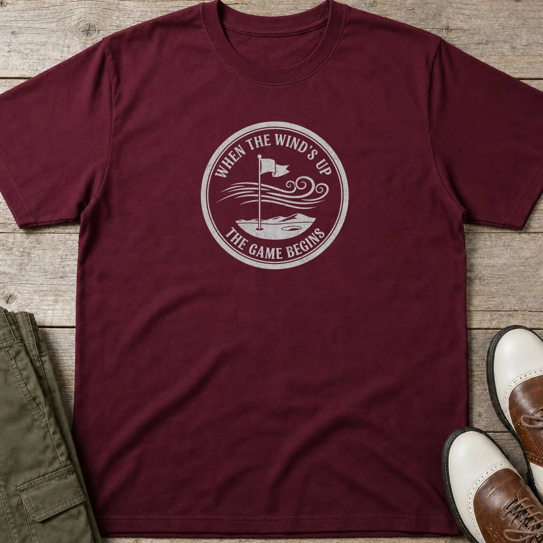 Wind's Up T-Shirt in Maroon lying on a plain floor. T-shirt is a unisex cut and 100 per cent cotton.