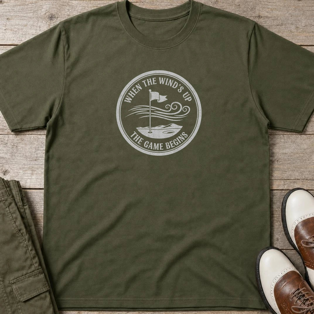 Wind's Up T-Shirt in Military Green lying on a plain floor. T-shirt is a unisex cut and 100 per cent cotton.