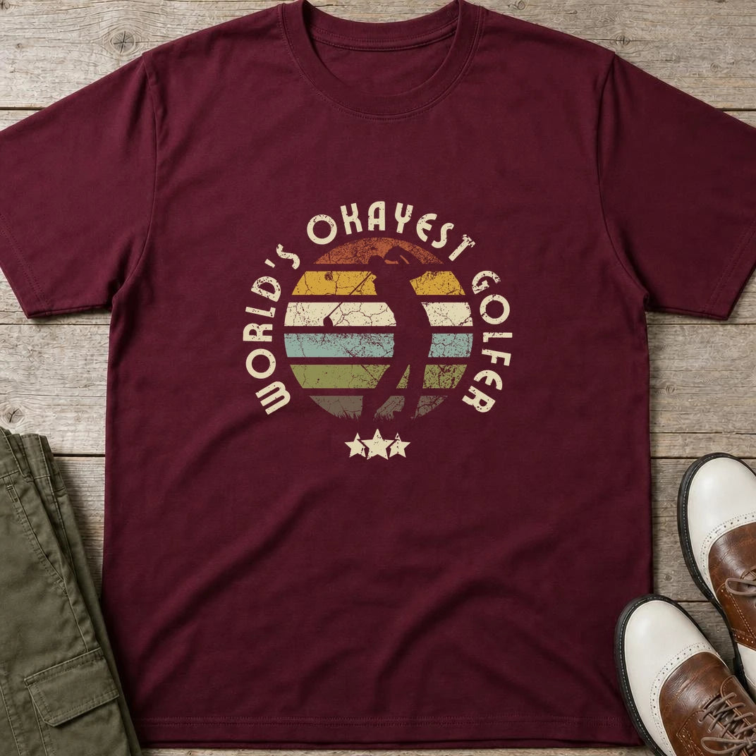 Okayest Golfer T-Shirt in Maroon lying on a plain floor. T-shirt is a unisex cut and 100 per cent cotton.